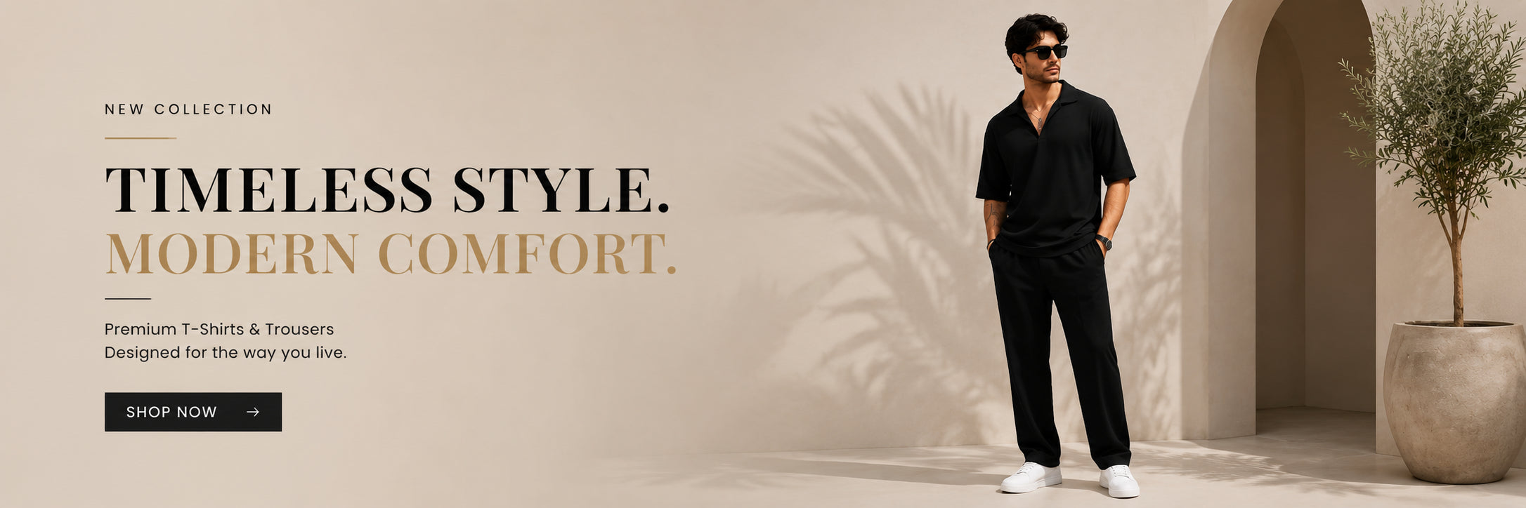 A man wearing a black short-sleeve button-up shirt and black trousers stands in a warm beige architectural setting with arches and a potted plant. Large text on the left reads 'TIMELESS STYLE.