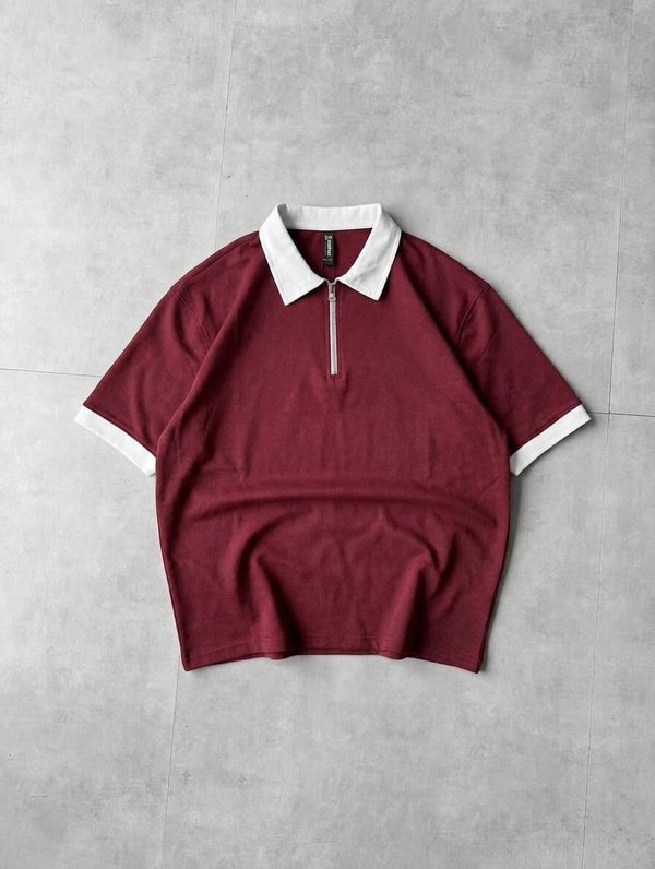Maroon t-shirt with white collar and trim on a gray background
