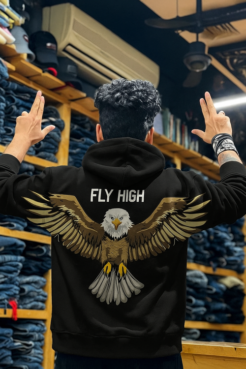 Person wearing a hoodie with an eagle design and 'Fly High' text in a denim store.