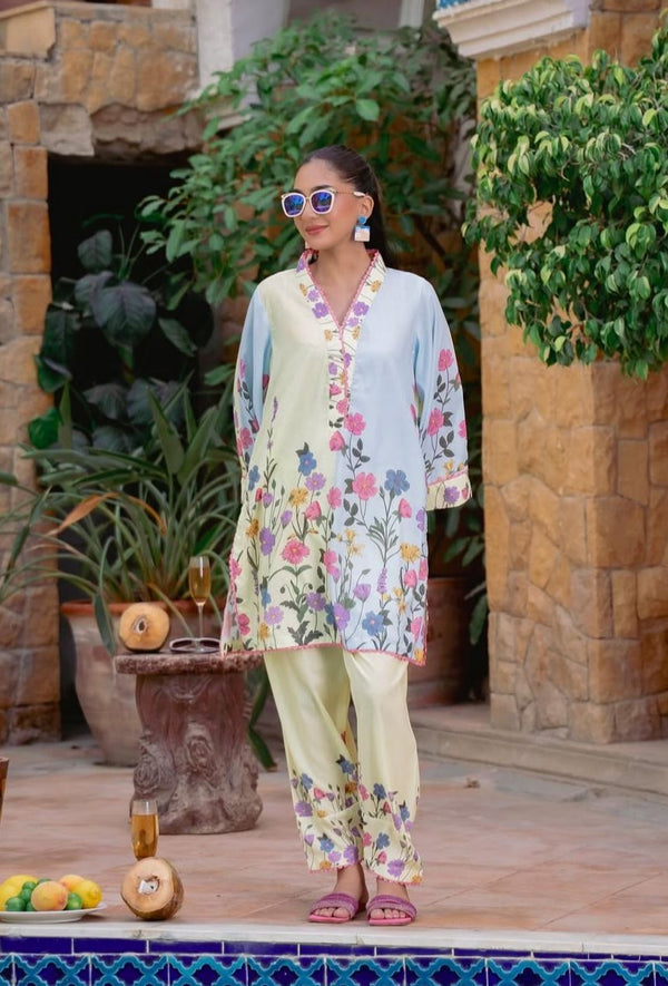 Woman in a floral outfit standing outdoors with plants and a pool in the background