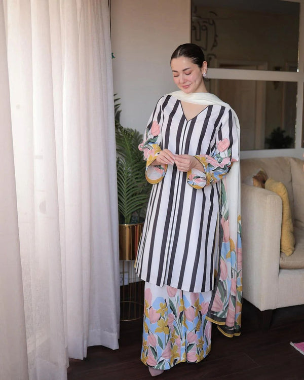 Woman wearing a black and white striped dress with floral patterns indoors.