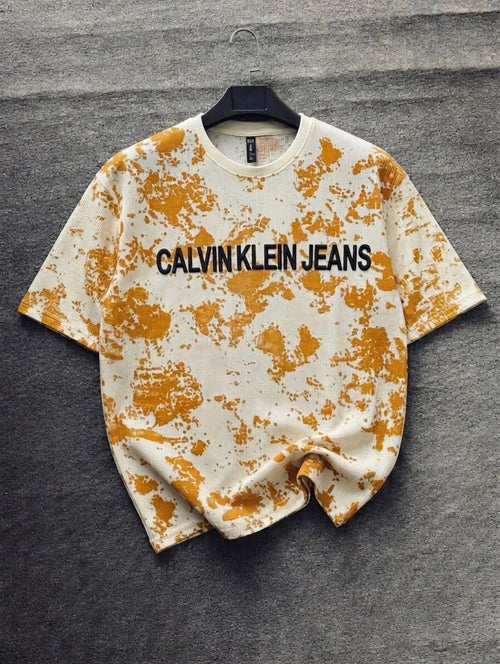 Calvin Klein Jeans t-shirt with orange splatter design on a gray background