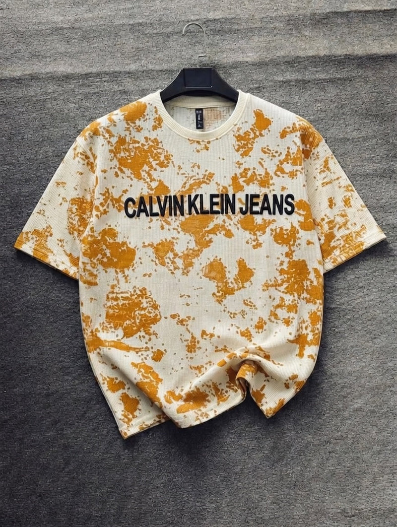 Calvin Klein Jeans t-shirt with orange splatter design on a gray background